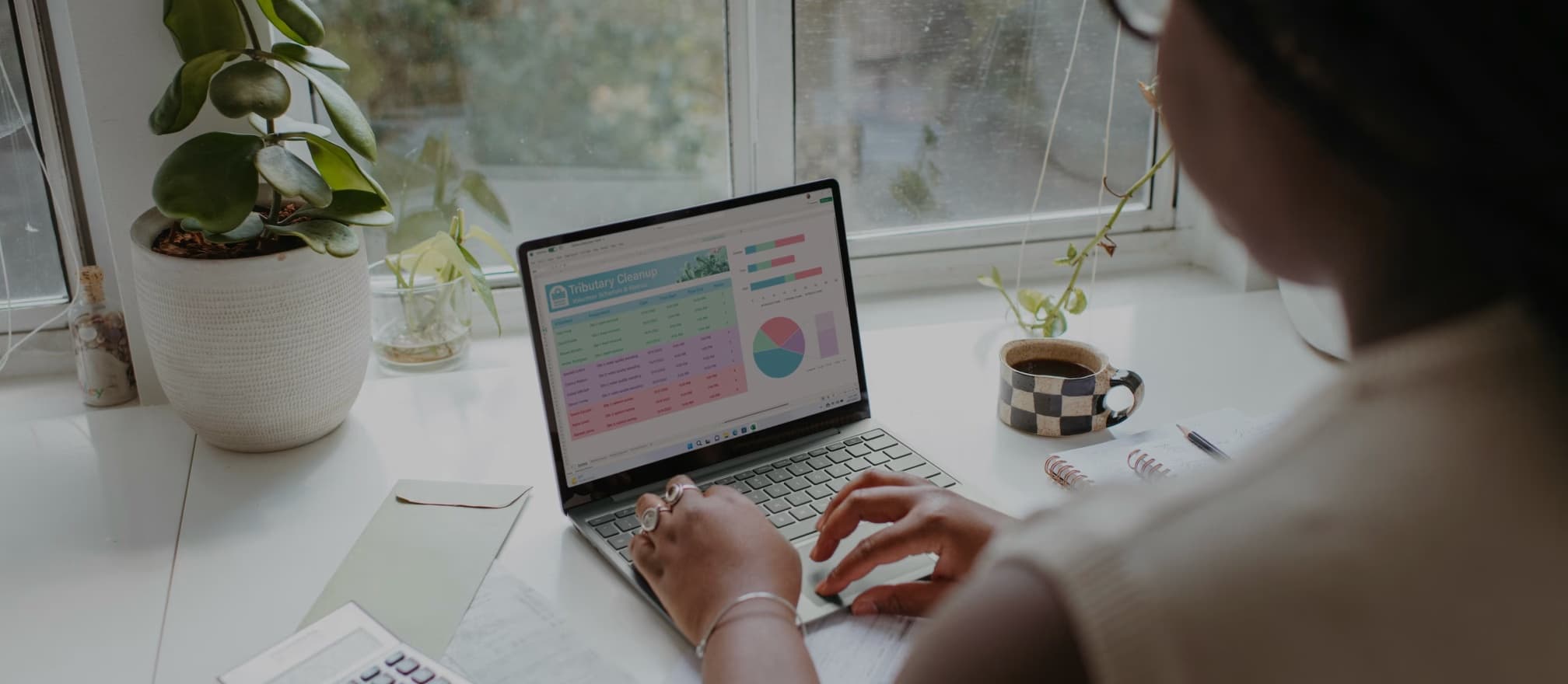 Person working on a laptop by the window with charts on screen